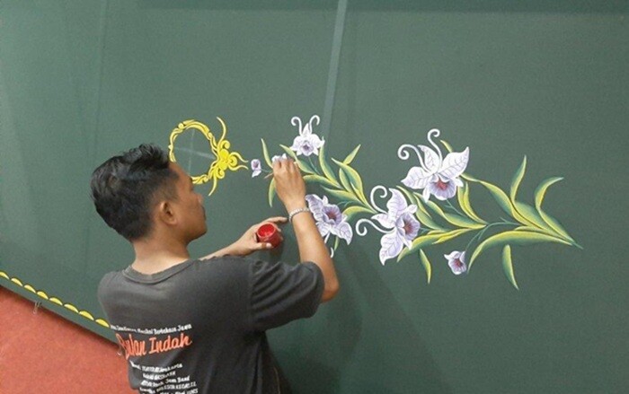 Seorang pelukis Nasrafa sedang melukis motif bunga untuk bahan hijab/jilbab.